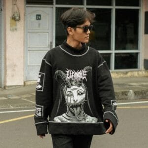 Stylish portrait of a man wearing a printed black sweater and sunglasses outdoors.