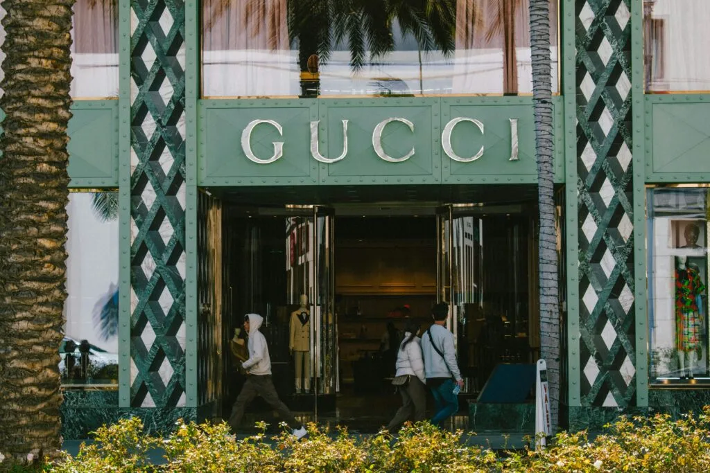 Gucci store facade with people passing by on a sunny day.
